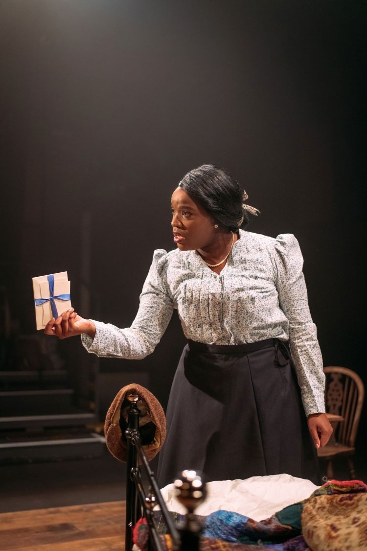 Actor in period clothing holds a bundle of letters in an outstretched arm